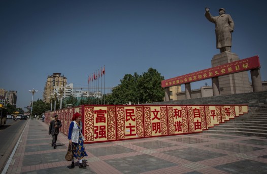 A Uighur woman walking past a statue of Mao Zedong in Kashgar City, northwestern Xinjiang, China, 2017. Photo credit: Guillaume Payen / SOPA Images / LightRocket via Getty Images.